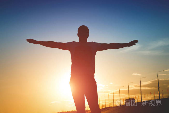 日落时分举起双臂的人的剪影