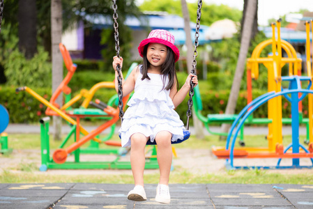 可爱的小女孩在公园里荡秋千玩得很开心。儿童游乐场