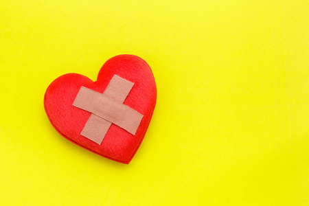 石膏或创可贴上红色的心在黄色背景上的形状。使用