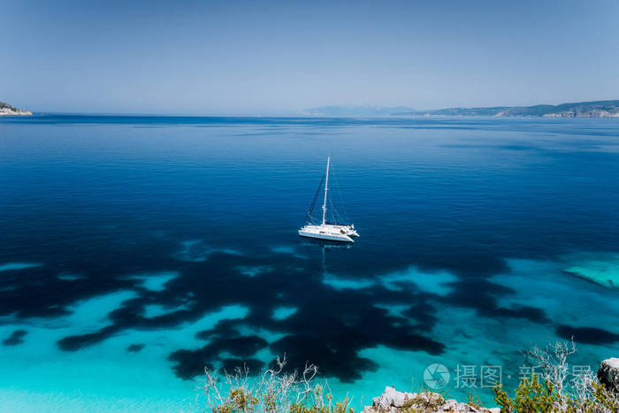 Fteri 海滩, Cephalonia 凯法利尼亚, 希腊。白色双体游艇在清澈的蓝色透明海水表面