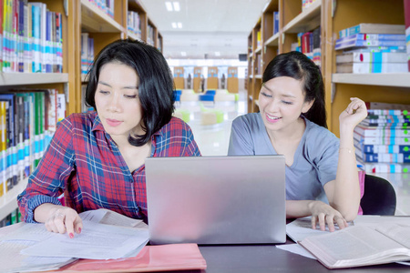 白人学生在图书馆里和朋友一起做功课的照片