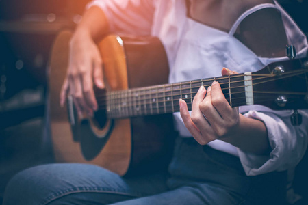 她正在酒吧里弹吉他, 灯光昏暗.照片