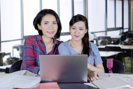 一个白种大学生的图片使用笔记本电脑, 同时与她的朋友在课堂上一起学习