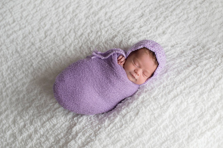 一个微笑, 两个星期的新生女婴襁褓在薰衣草包装和穿着钩编帽子。在演播室拍摄的白色毯子