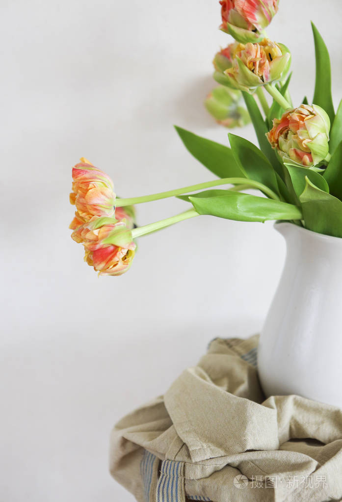 在质朴的木椅上的白色花瓶郁金香花束