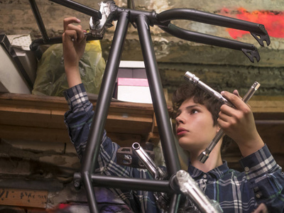 在车库里修理自行车车的年轻人肖像