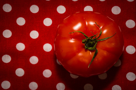 一只红色的西红柿躺在红茶巾上