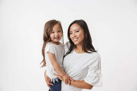 照片的欢快的年轻的亚洲妇女的母亲与她的小女孩的女儿孤立的白色墙壁背景