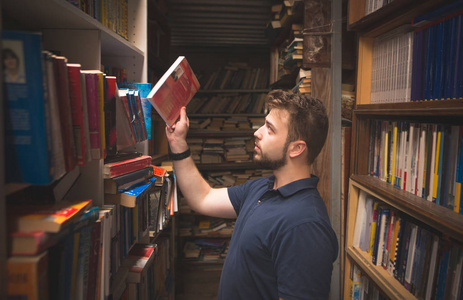 有胡子的人的肖像, 他从图书馆的书架上拿书。学生在旧公共图书馆里选书。在大气库中搜索书籍