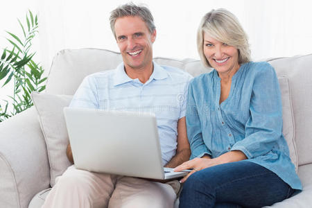 一对幸福的夫妇在沙发上一起用笔记本电脑看摄像机