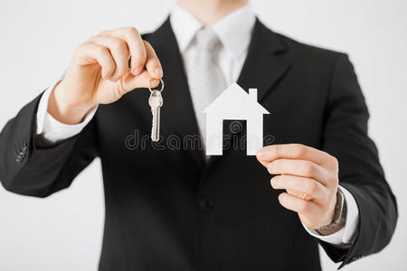 拿着房子钥匙和纸房子的人