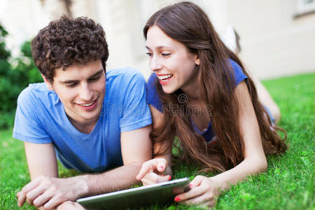 夫妇在草坪上使用数码平板电脑