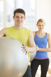 自信的情侣在健身房里打健身球照片