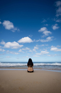 坐在沙滩上望着地平线的女人