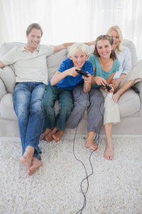 孩子们坐在沙发上一起玩电子游戏