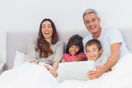 快乐的一家人躺在床上用笔记本电脑