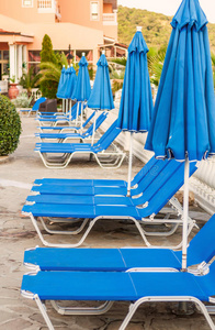 泳池边的蓝色躺椅和雨伞图片