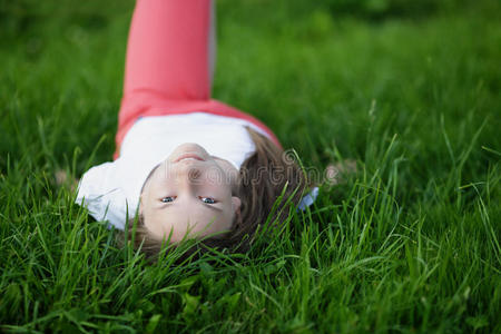 年轻漂亮的女孩躺在草地上看着镜头