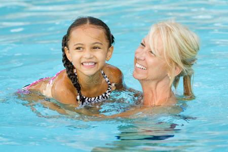 母亲和混血女孩在游泳池里玩耍