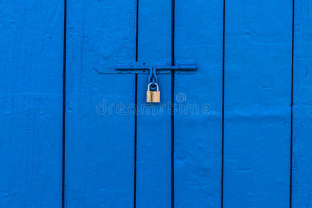 蓝色木门上的旧铜挂锁图片