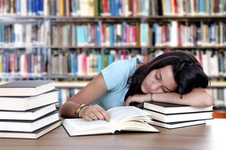 疲倦的学生睡在图书馆的书桌旁