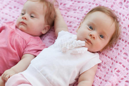 可爱的小双胞胎躺在粉红色的毯子上。