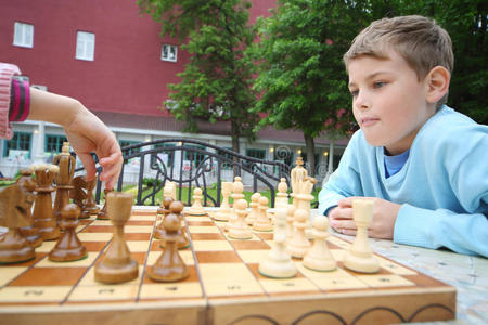 男孩看起来像女孩的手在棋盘上移动棋子