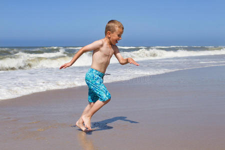 在沙滩上躲避海浪的男孩