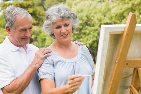 快乐退休妇女在画布上画画与丈夫交谈