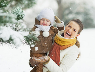 快乐的妈妈和宝宝在树枝上玩雪