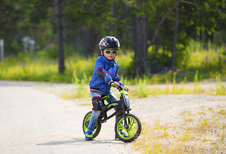 一个穿着头盔和眼镜的快乐男孩骑着自行车