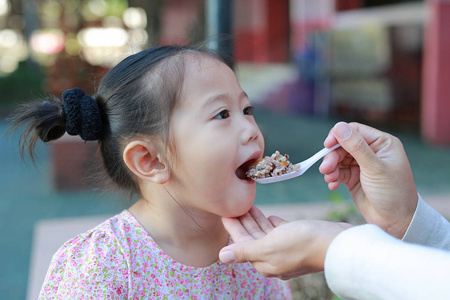 母亲用勺子喂孩子吃食物