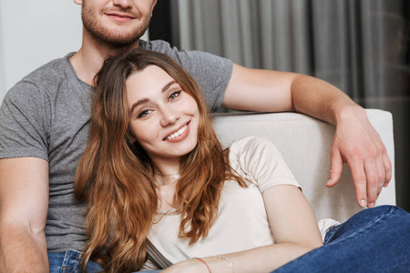 幸福年轻情侣的形象坐在沙发上在家中看相机