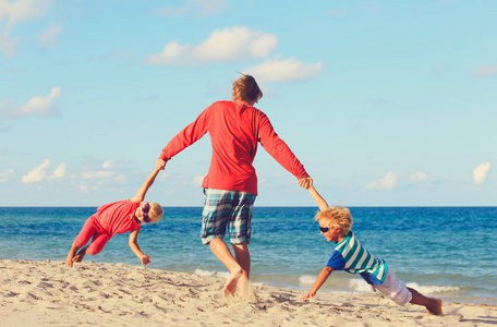 父亲带儿子和女儿在海滩玩