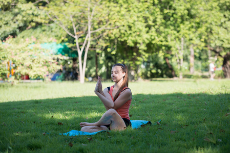 在公园户外练习瑜伽的年轻女子。健康的生活方式和放松的概念