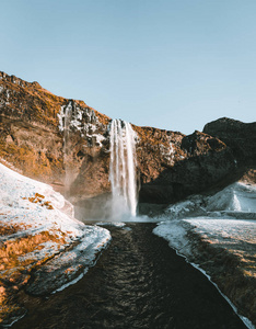 美丽的风景从冰岛的 Seljalandsfoss 瀑布在晴朗的天与蓝色的天空和雪