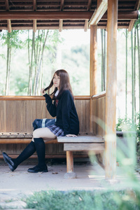 亚洲日本学校女孩服装的肖像坐在公园户外电影复古风格