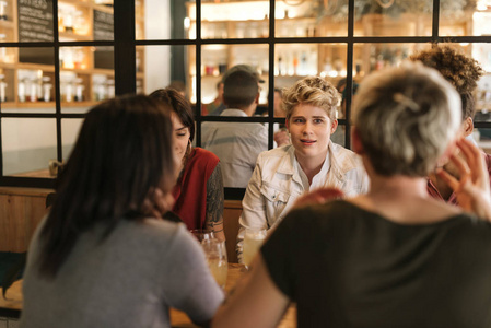 不同的一群年轻的女性朋友坐在一张桌子上, 在一个时髦的酒吧喝酒, 一起聊天