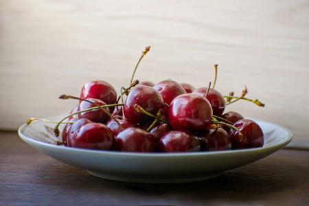 木桌上盘子上新鲜可口的樱桃果