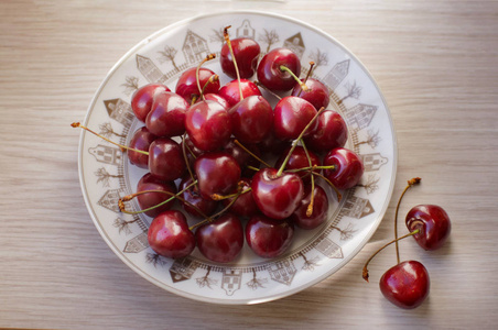 木桌上盘子上新鲜可口的樱桃果