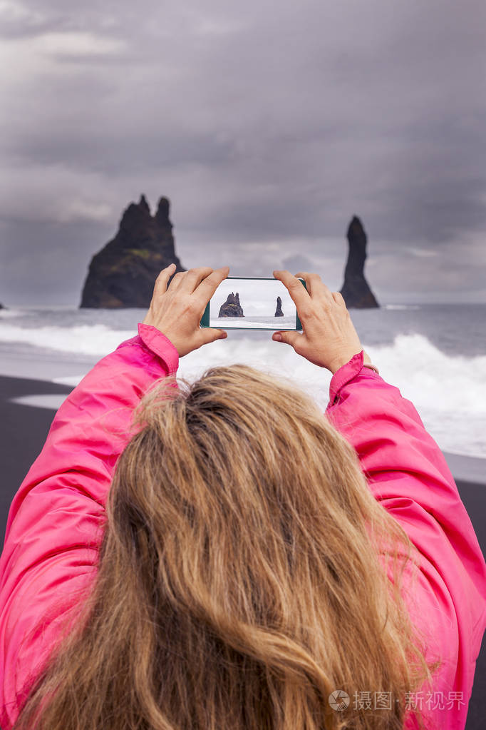 迷人的成熟女人拍照与智能手机在 vik 冰岛的黑色海滩