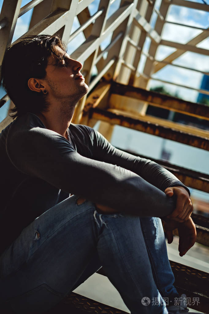 性感的男人在金属楼梯上晒太阳