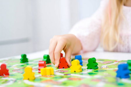 棋盘游戏和儿童休闲概念小金发女孩手持红色的人的身影。黄色, 蓝色, 绿色木片在儿童玩