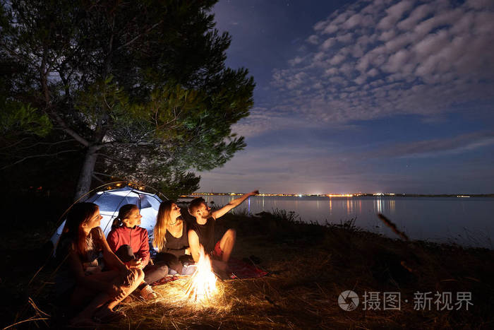 照片 人物 一群四游客坐在海边的篝火前的旅游帐篷树下, 胡子男子指着