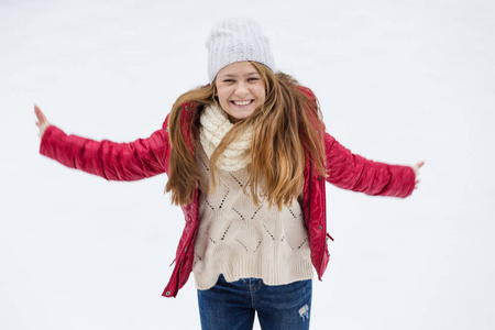 一个年轻漂亮的金发女郎, 长着一头金色的长发, 享受着第一场雪。红夹克, 白帽子和手套。冬季时间