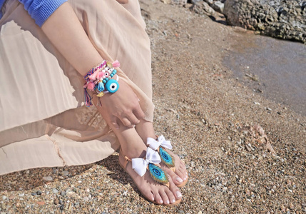 女人做广告传统希腊凉鞋和海滩上的珠宝