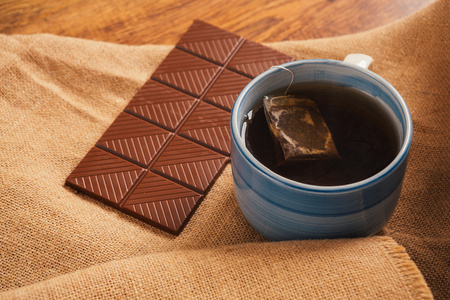 蓝杯茶和巧克力上背景麻布
