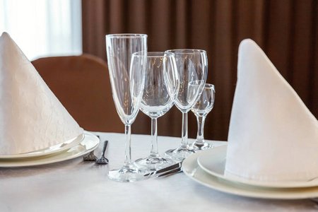 眼镜, 餐巾折叠在一个金字塔, 服务于晚餐在餐厅与舒适的室内。婚礼装饰品和食物用品, 由餐饮服务安排在一个大桌子上, 上面铺着白