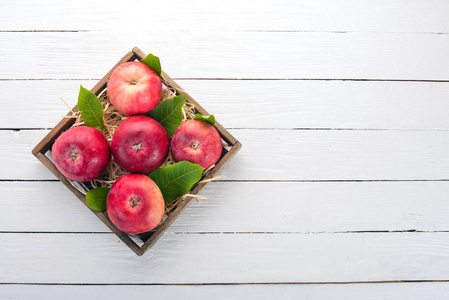新鲜的红苹果在一个木箱里。有机食品。在白色的木质背景。顶部视图。文本的可用空间