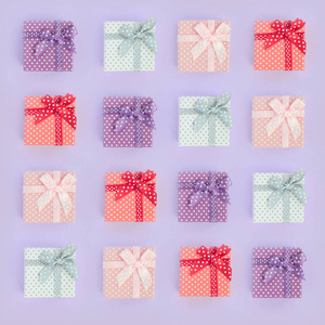 一堆带有丝带的小彩色礼品盒位于紫罗兰色的背景上。简约平躺顶视图模式
